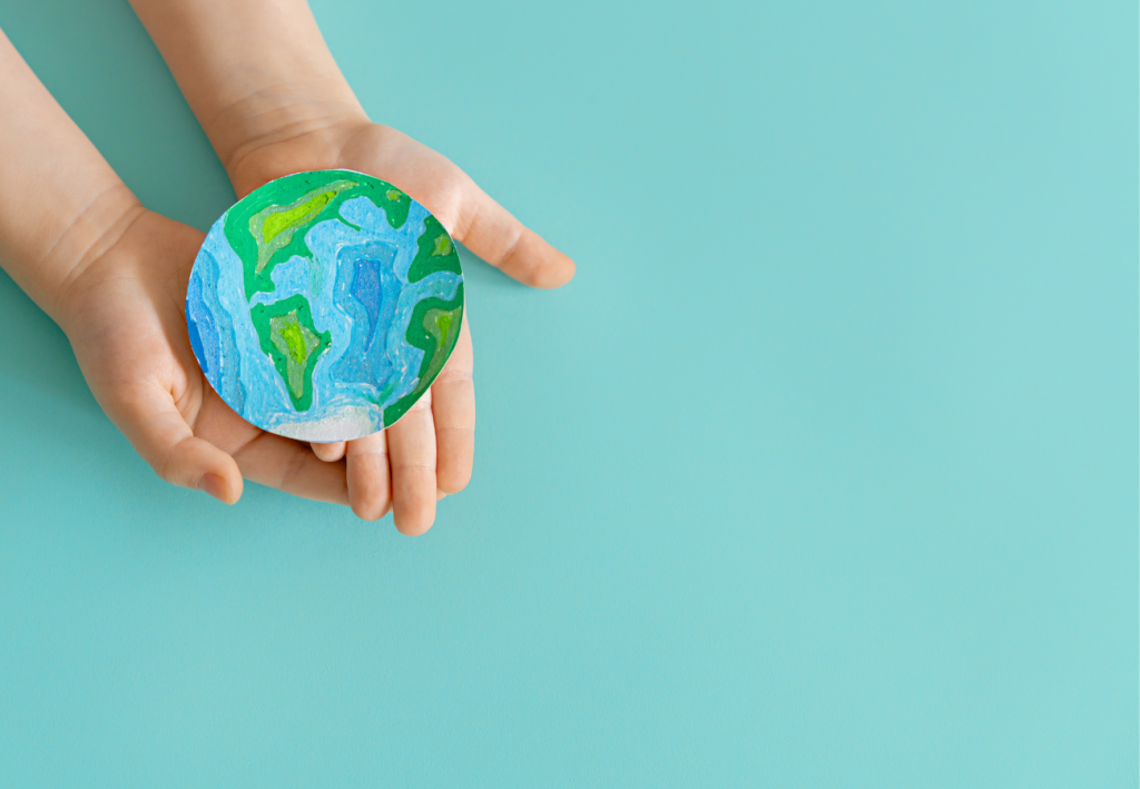 Child's hands gently holding a colourful, cut-out drawing of Earth, symbolising the importance of teaching young generations about environmentalism and Earth Day.
