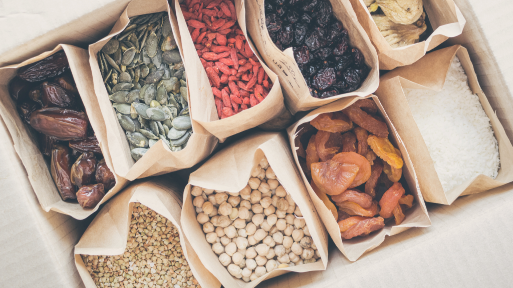 Paper bags filled with refillable dried goods such as rice and grains, promoting sustainable pantry swaps for 2025. The image reflects zero-waste shopping and larder organisation tips from the blog.